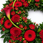Detail van rode rozen, calla’s en gerbera’s in de rouwkrans