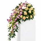 Crème-lila rouwbloemstuk met afhangende bloemen naar links op witte achtergrond